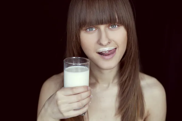 Chica lame su lengua del bigote de la leche con un vaso de mil —  Fotos de Stock