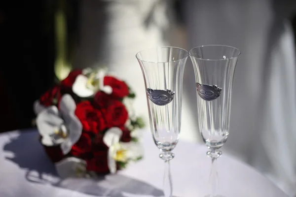 Dois copos de casamento e buquê de noiva na mesa — Fotografia de Stock