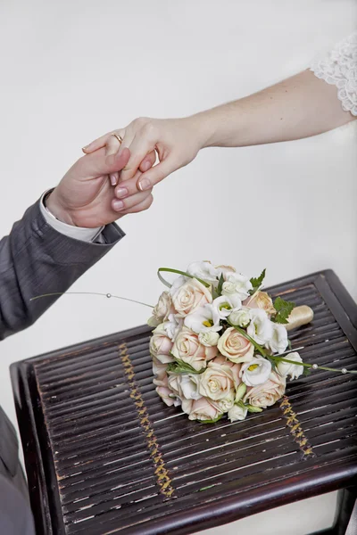 Hands and rings on wedding bouquet — Stock Photo, Image