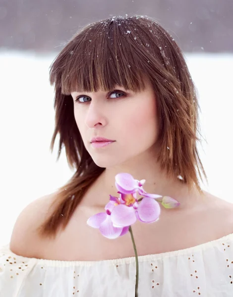 Sexy girl in the park in winter, with a pink orchid — Stock Photo, Image