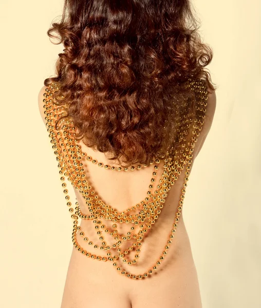 Sexy chica morena con un conjunto de cuentas de oro en la espalda desnuda — Foto de Stock