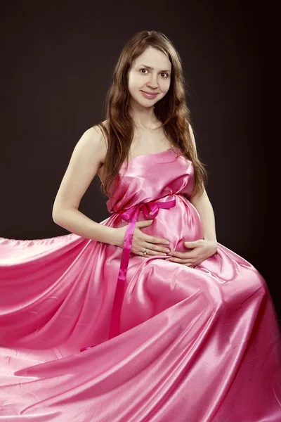 Bela menina grávida em um vestido rosa — Fotografia de Stock