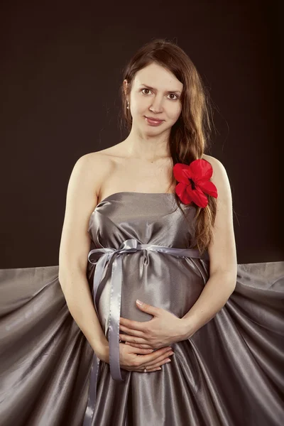 Kırmızı çiçekli gri elbiseli güzel bir hamile kadın — Stok fotoğraf