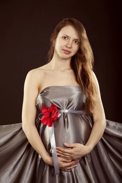 孕妇在一朵红色的花灰色连衣裙 — 图库照片