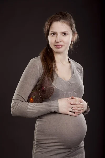 Szép terhes nő egy szürke ruhát egy játék macska — Stock Fotó