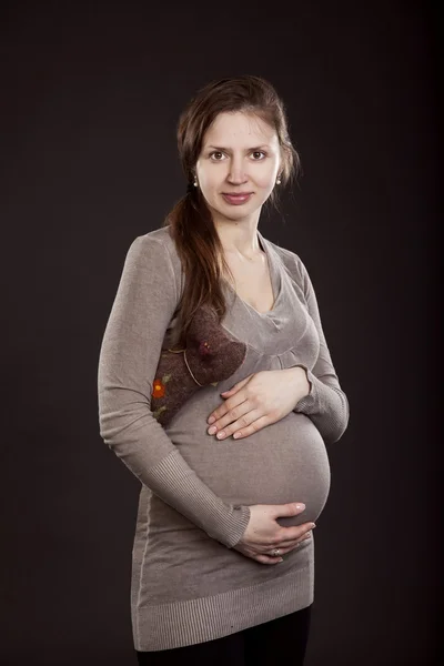 Krásná těhotná žena v šedé šaty s cat hračka — Stock fotografie