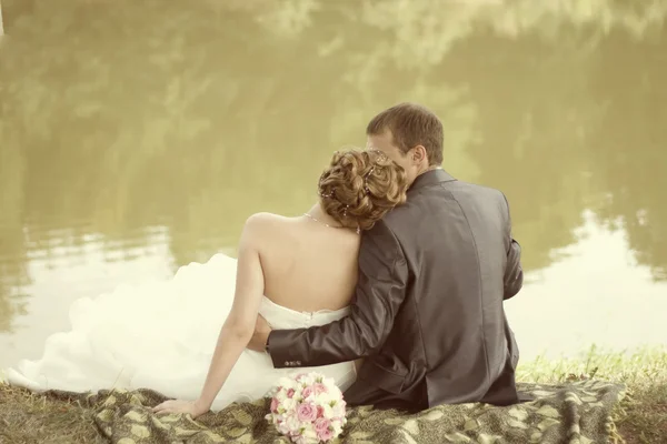 Bruden och brudgummen tittar på sjön — Stockfoto
