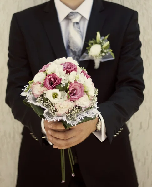 Le marié tient un bouquet de mariée — Photo