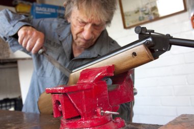 Man repairing a gun in his workshop clipart