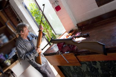 Man repairing rifle guns in his workshop with motion blur to man clipart