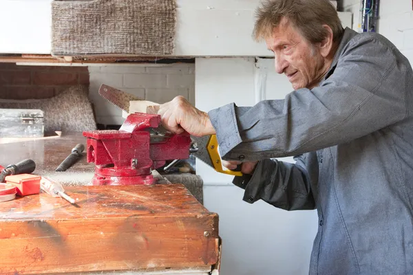 Alter Mann sägt in Werkstattschuppen — Stockfoto