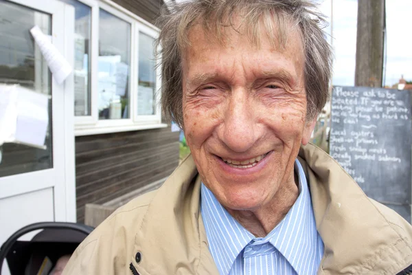 Пожилой мужчина в свои 80 улыбается в камеру — стоковое фото