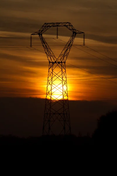 Puesta de sol detrás de un pilón eléctrico — Foto de Stock