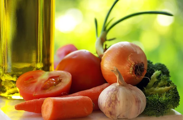 Оливковое масло и овощи на зеленом фоне . — стоковое фото