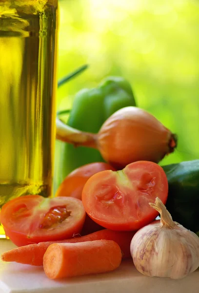 Olive oil and vegetables in green background. — Stock Photo, Image