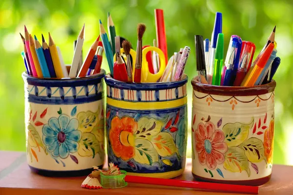 Trois pots, crayons et objets scolaires sur fond vert — Photo