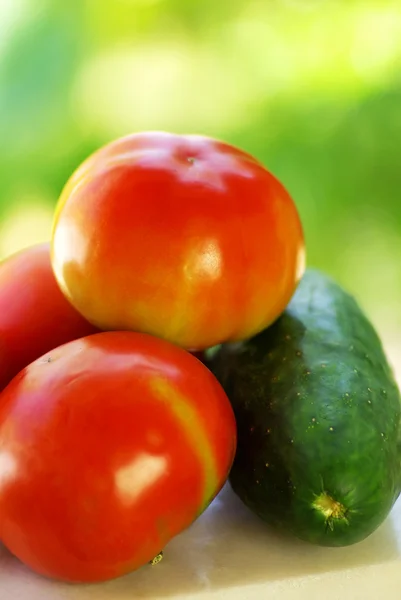 Tomaat en komkommer op groene achtergrond — Stockfoto