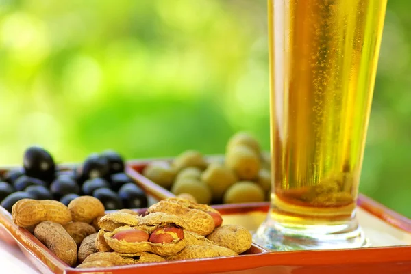 Бокал пива с арахисом и оливками — стоковое фото