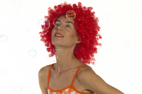 Beautiful woman in an orange wig with soap bubbles — Stock Photo, Image