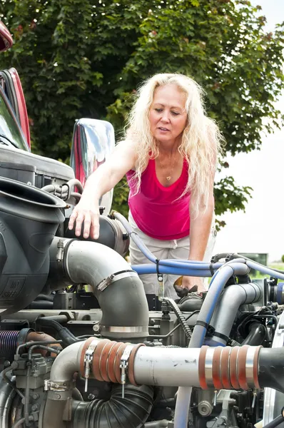 Hübsche blonde Frau öffnet eine Motorhaube eines Lastwagens. — Stockfoto