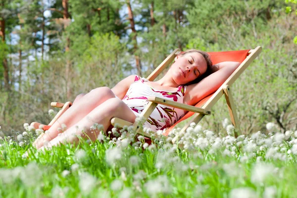 Ung kvinna ligga i en solstol — Stockfoto