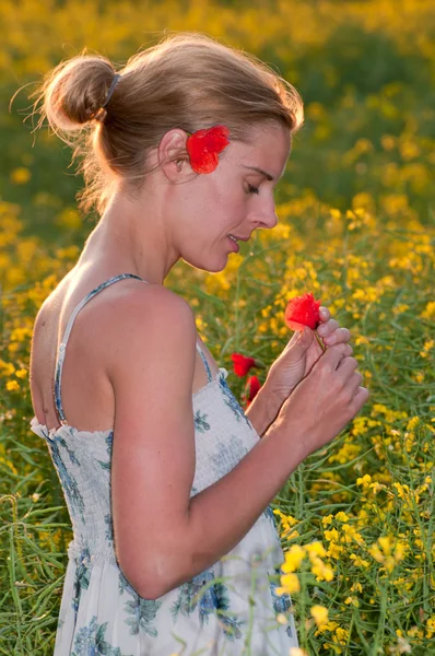 Mladá krásná žena sbíráme červené Vlčí máky v poli řepky — Stockfoto