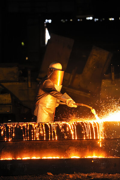Worker using torch cutter to cut through metal