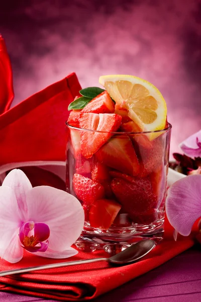 Aardbeien met orchid op rode tafel — Stockfoto