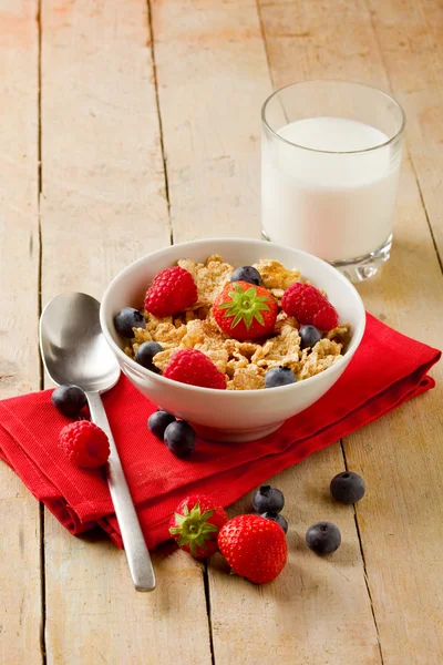 Corn flakes with berries on wooden table — Stock Photo, Image