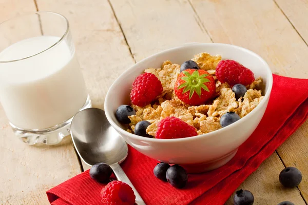 Corn flakes with berries on wooden table — Stock Photo, Image