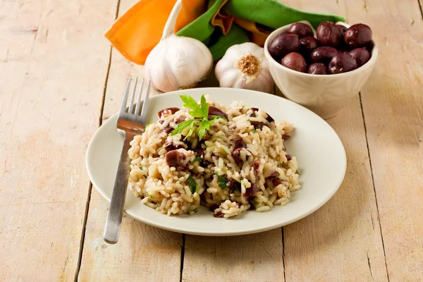 Risotto with black olives on wooden table — Stock Photo, Image
