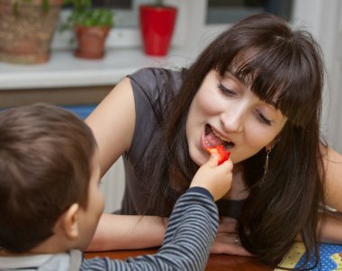 Boy gives a piece of red pepper to mother clipart