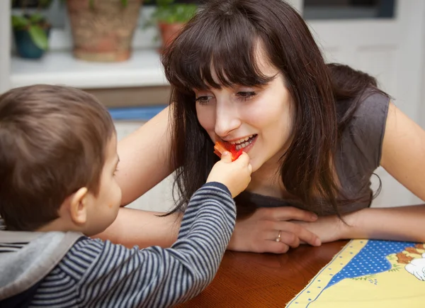 Boy gives a piece of red pepper to mother — Stock Photo, Image