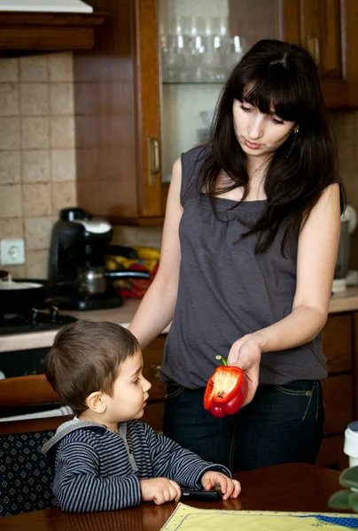 Мать предлагает своему ребенку красный болгарский перец — стоковое фото