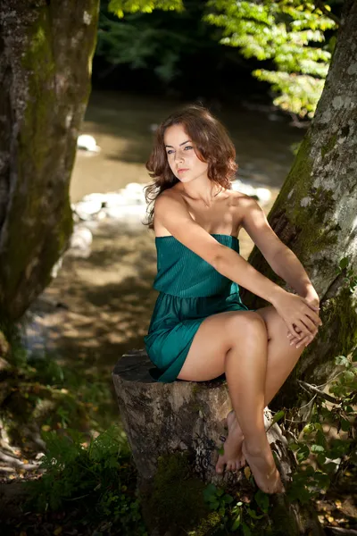 Young woman sitting on a stump — Stock Photo, Image