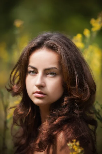 Retrato de uma jovem mulher no campo de flores — Fotografia de Stock