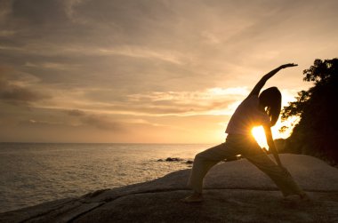 Asian girl performing yoga on beach clipart