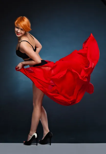 Mladá žena s rukama nahoře drží červeným šátkem ve větru — Stock fotografie