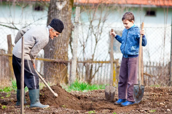 Senior bonde med barnbarn i trädgården — Stockfoto