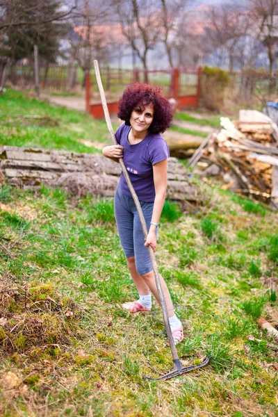 Юная леди с граблями весной убирает сад — стоковое фото