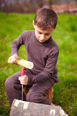 Boy sculpting in a log with a chisel clipart