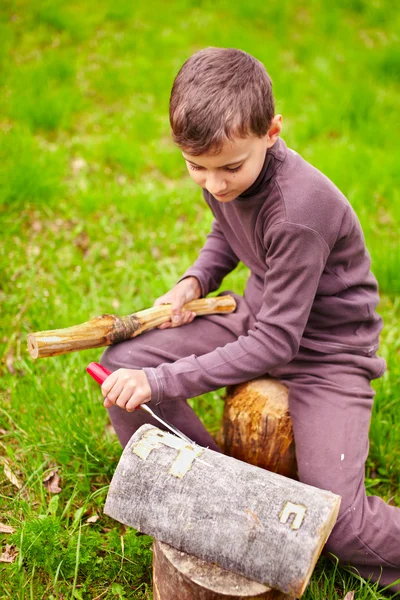 男孩用凿子雕刻在日志中 — 图库照片