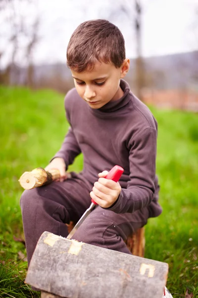 Rapaz a esculpir num tronco com um cinzel — Fotografia de Stock