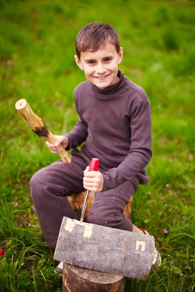 Niño esculpiendo en un tronco con un cincel — Foto de Stock