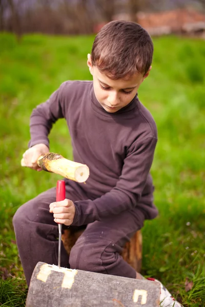 Rapaz a esculpir num tronco com um cinzel — Fotografia de Stock