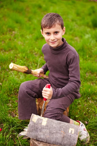 Junge, der mit einem Meißel in einen Baumstamm meißelt — Stockfoto