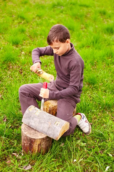Boy sculpting in a log with a chisel Royalty Free Stock Images