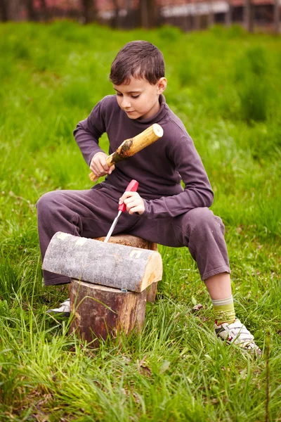 Boy sculpting in a log with a chisel Royalty Free Stock Photos
