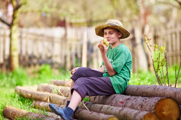 Joyeux garçon assis en plein air sur des billes de pin — Photo