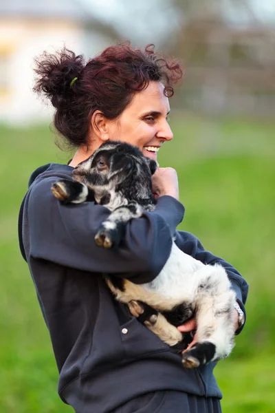 Giovane donna con capra bambino all'aperto — Foto Stock